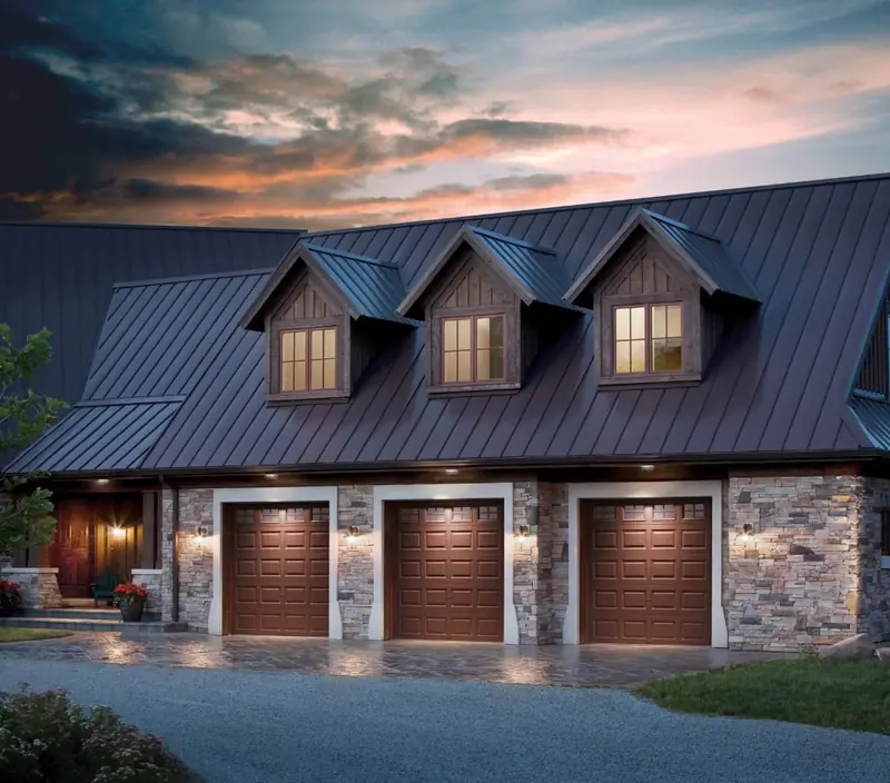 Brown carriage-house garage doors photographed at dusk